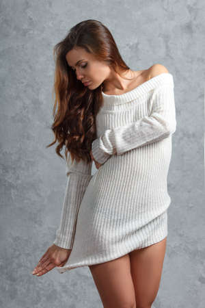 Beautiful young brunette woman in sweater over gray backgroundの写真素材