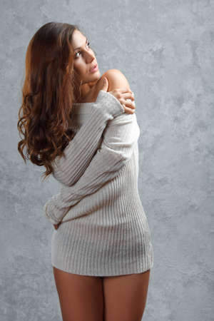Beautiful young brunette woman in sweater over gray backgroundの写真素材