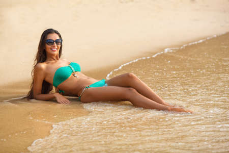 tanned beautiful brunette laying on tropical beachの写真素材