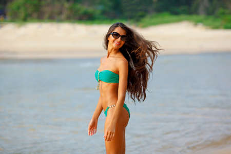 tanned beautiful brunette walking along the tropical beachの写真素材