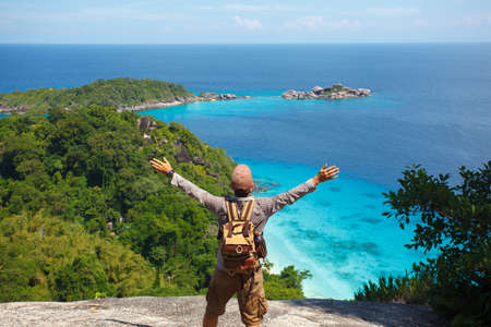 traveller with backpack standing on the rocks above the tropical seaの写真素材