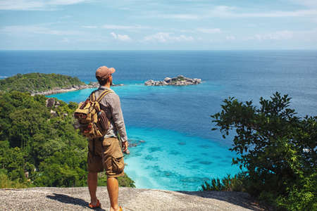 traveller with backpack standing on the rocks above the tropical seaの写真素材