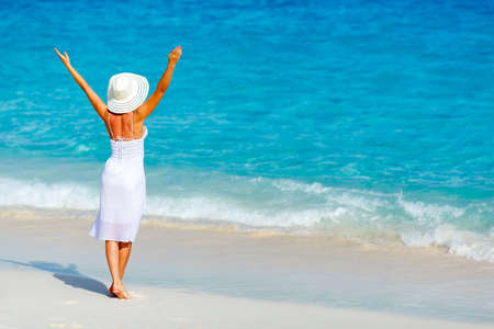 Young woman in a white dress walking on the tropical beautiful beachの写真素材
