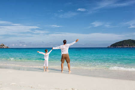 Happy father and son playing together at tropical beachの写真素材