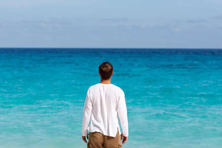 happy young man on the tropical white sand beachの写真素材