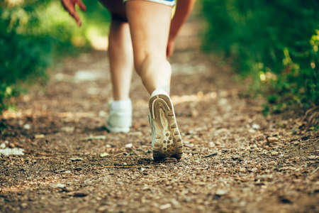 closeup woman runner shoe on park trail