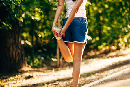 yong sporty woman streching her leg in the summer parkの写真素材