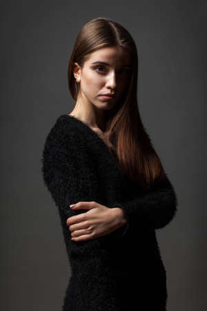 fashion caucasian beautiful woman low key portait over dark background, hands on chestの写真素材