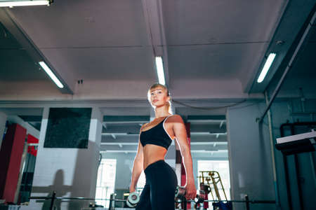 strong fitness woman holding dumbbells in the gymの写真素材