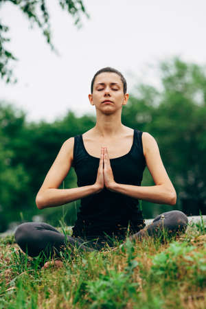 woman sitting in lotus pose outdoors in the parkの写真素材