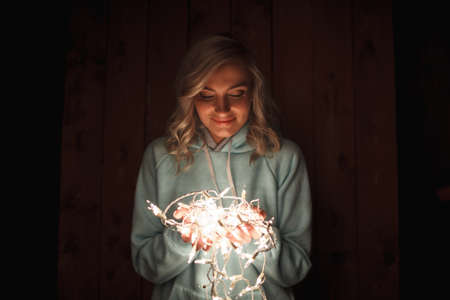 blonde woman holding electric garland, wooden background, film color effectの写真素材