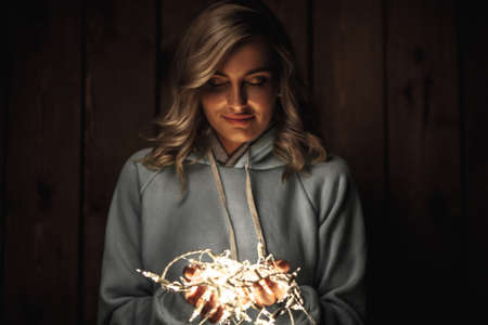 blonde woman holding electric garland, wooden background, film color effectの写真素材