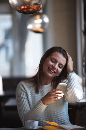 smiling woman using her smartphone phone at cafeの写真素材