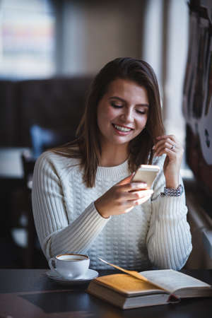 smiling woman using her smartphone phone at cafeの写真素材