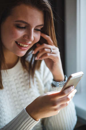 smiling woman using her smartphone phone at cafe, closeup viewの写真素材