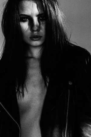 black and white portrait of a woman with styling inspired with rock fashion. Strong grain added as...