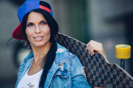 yong brunette woman holding longboard behind head, closeup portraitの写真素材