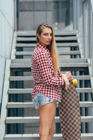 young beautiful blonde woman with longboard on staris in the streetsの写真素材