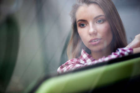 closeup portrait of young woman looking far away through the glassの写真素材