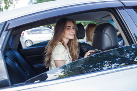 teenage beautiful girl sitting in the rear of gray carの写真素材