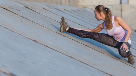 Portrait of a happy young fitness woman stretching outdoors on sunset
