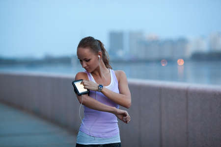 sporty woman on river bank wearing sport armband looking farawayの写真素材