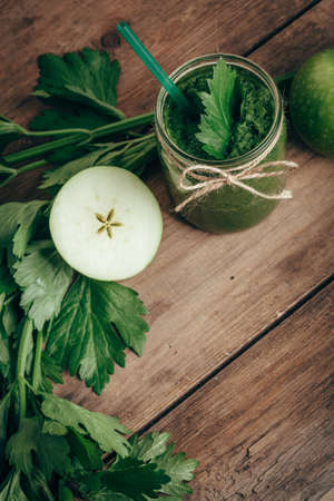 Overhead view of green smoothie with celery and apple on rusic wooden tableの写真素材