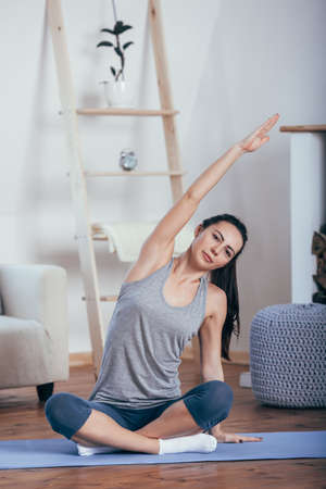 Young cheerful attractive woman practicing yoga, sitting in Sukhasana poseの写真素材