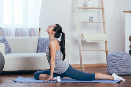 Young attractive smiling woman practicing yoga at homeの写真素材