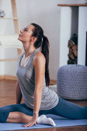 Young attractive smiling woman practicing yoga at homeの写真素材