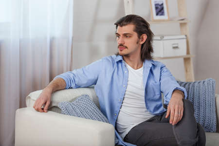 Young man sitting on sofa at homeの写真素材