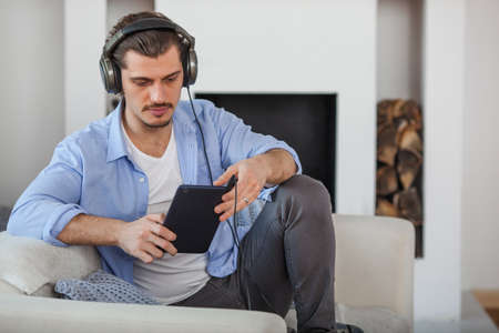 Handsome guy listening to music on internet with tabletの写真素材