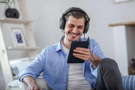 Handsome happy man looking to the dark blue tablet