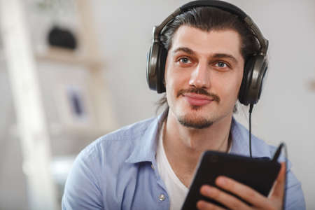 Handsome happy man looking to the dark blue tabletの写真素材