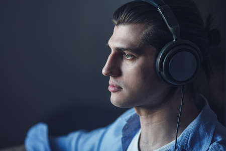 Music in his mind. Portrait of young man wearing headphones and looking awayの写真素材