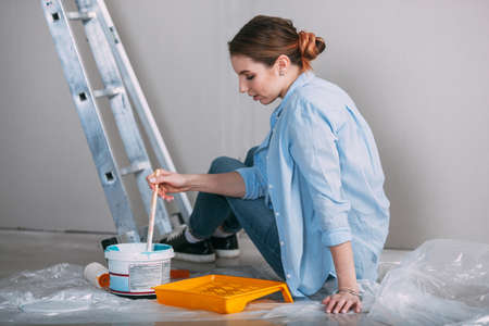 woman sitting on the floor and mixing wall paintの写真素材