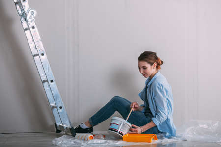 woman sitting on the floor and mixing wall paint