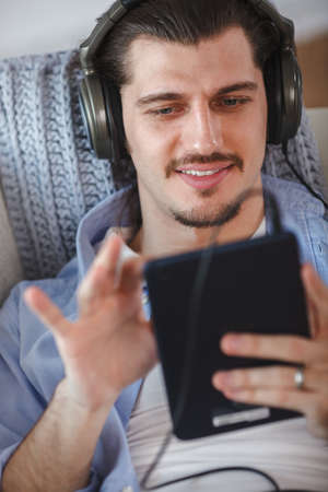 Handsome guy listening to music on internet with tabletの写真素材