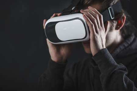 man standing in virtual reality helmet before dark backgroundの写真素材