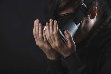 man standing in virtual reality helmet before dark backgroundの写真素材