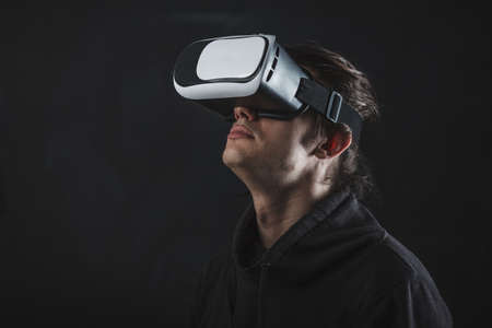 man standing in virtual reality helmet before dark background