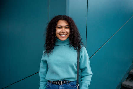 young woman waering sweater looking at camera againts the aqua color wallの写真素材