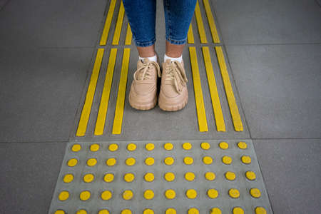 Young woman foots on floor with yellow blind markingの写真素材