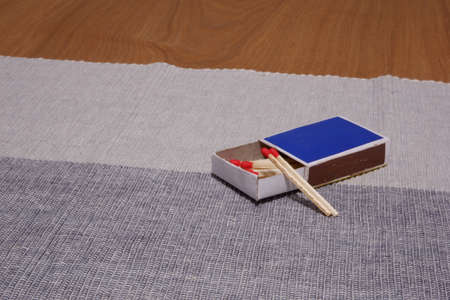 New match sticks and matchbox on a two-colour towel on a wood table