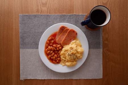 A delicious home style breakfast with scrambled egg, beans in tomato sauce, luncheon meat and...