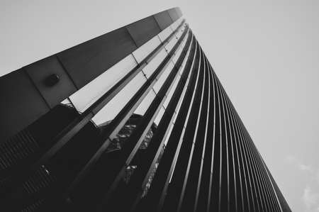 tall curved steel and glass skyscraper office building with gray grey sky in black and whiteの写真素材