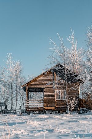 Winter season, landscape picture of a village covered by snow at sunset, country landscape with timber fence, holiday house made with wood, abandoned house, frozen treesの写真素材