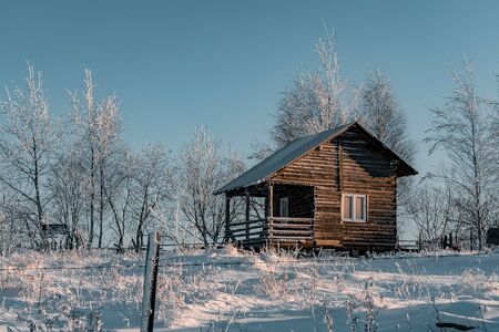 Winter season, landscape picture of a village covered by snow at sunset, country landscape with timber fence, holiday house made with wood, abandoned house, frozen treesの写真素材