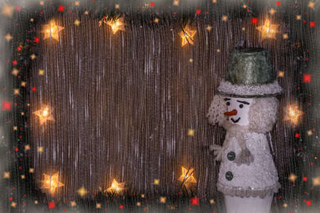 New Years and Christmas background with a snowman, glowing garland of stars, fir branches, lights.の写真素材