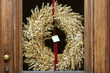 The front door has a glass insert and a wreath of dry grass of golden color.の写真素材